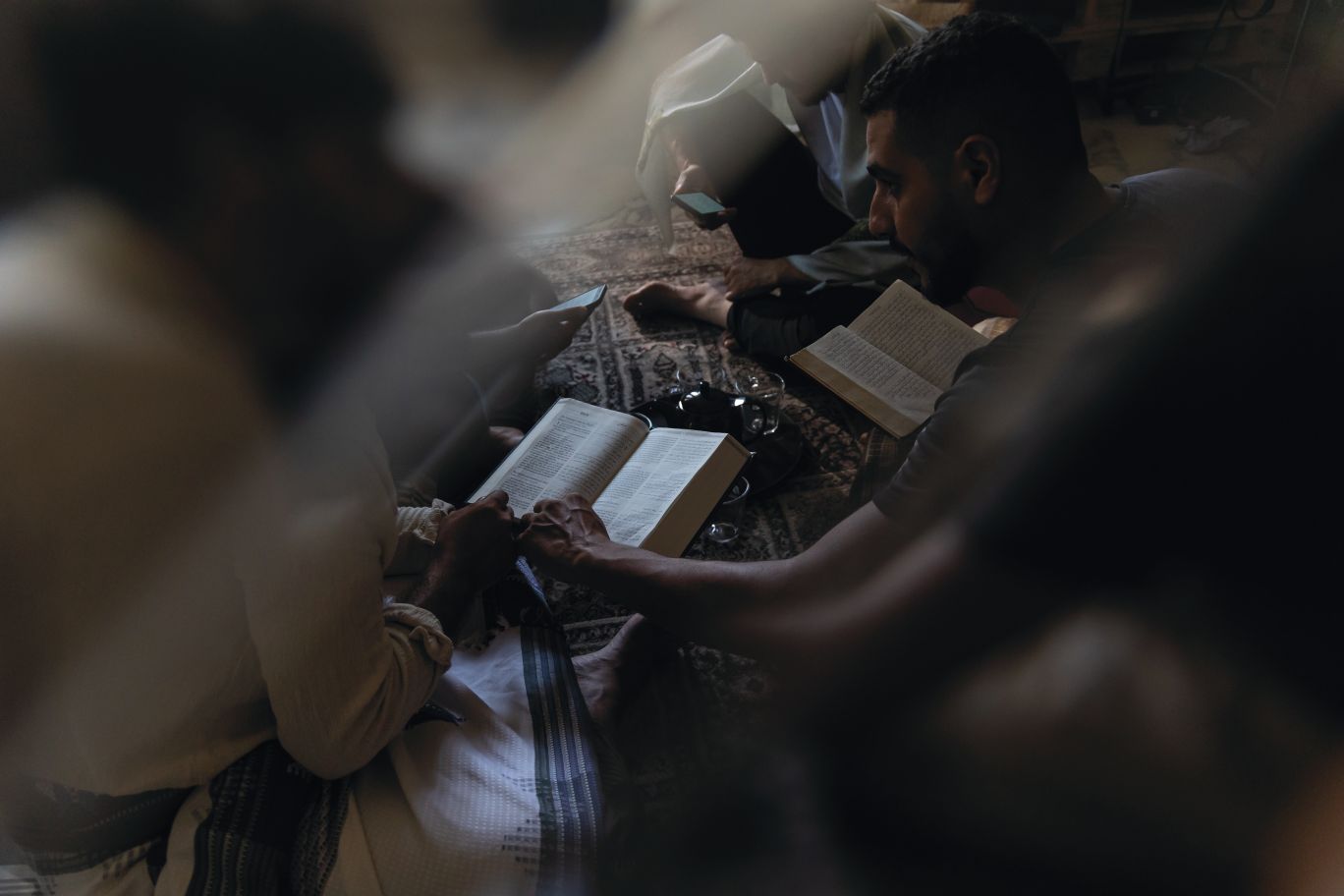 Vīrieši uz grīdas lasa Bībeli.