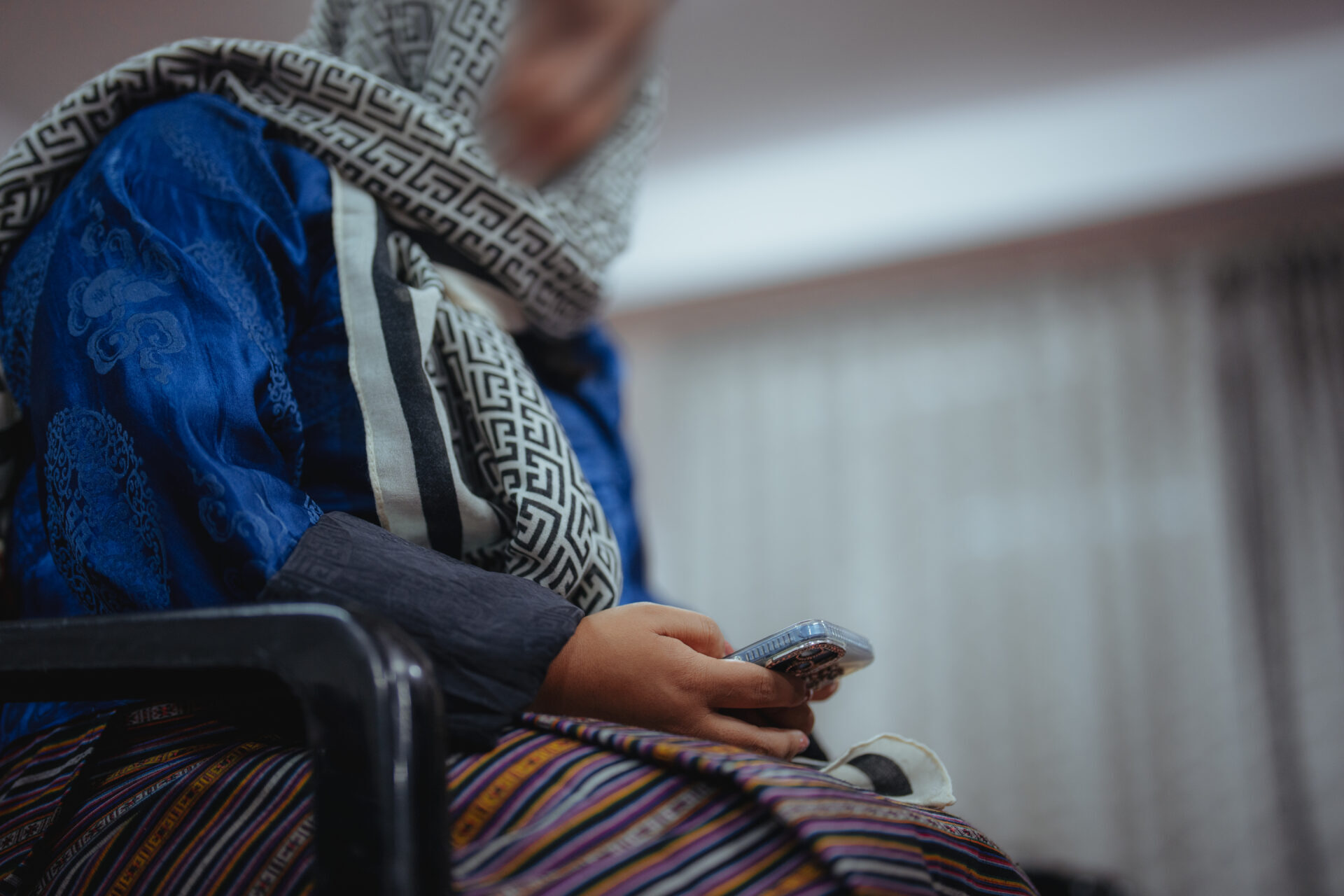Sieviete skatās savā mobilajā tālrunī.